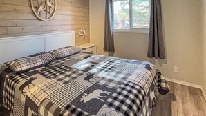 Ein Schlafzimmer mit einem Bett, einem Deckenventilator, einem Fenster mit Vorhängen und einer an der Wand befestigten Uhr.