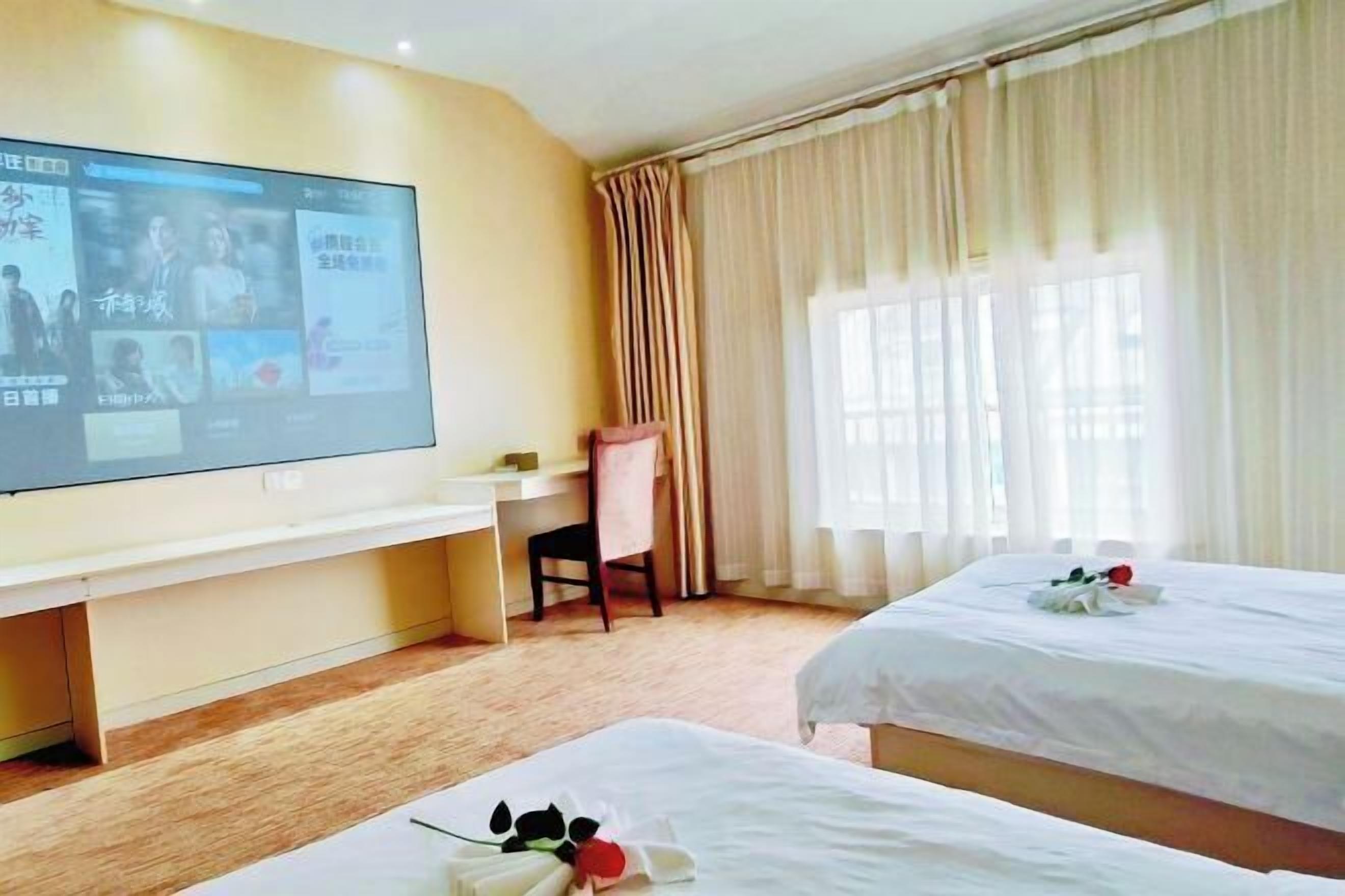 A hotel room with a TV, two beds, a desk, and a chair.
