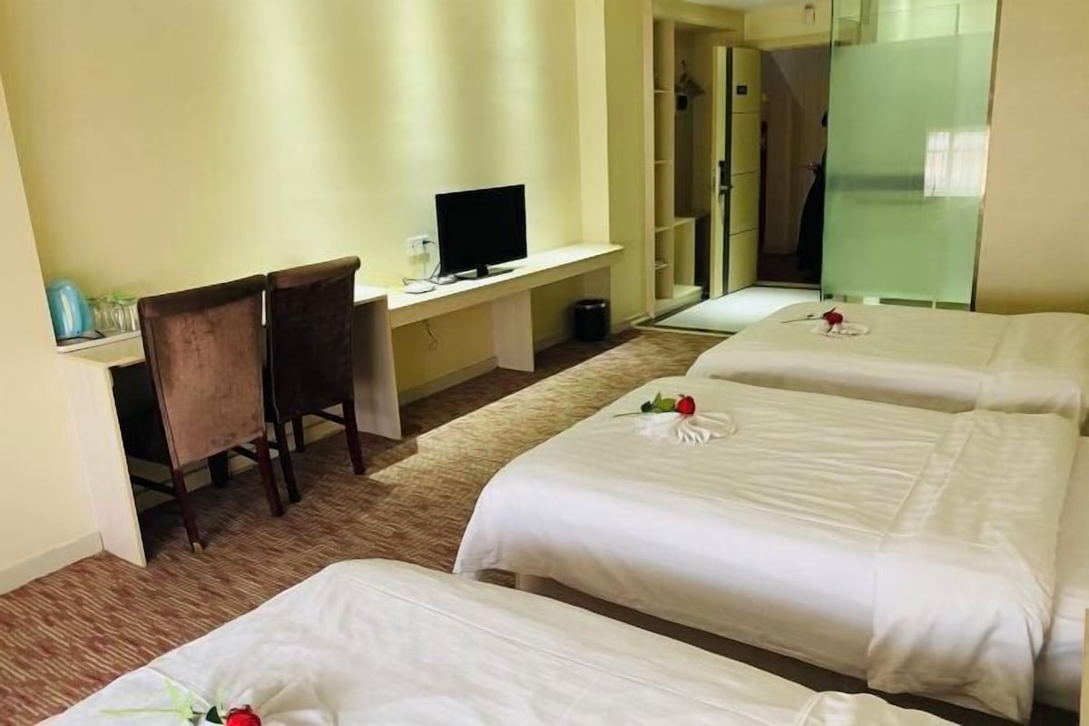 Habitación de hotel con dos camas, un escritorio con computadora y una silla.