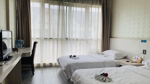 A hotel room with two beds, a desk with a computer, a chair, and a large window with sheer curtains. - Xuancheng Guangde Wanjia Express Inn (Guangde)