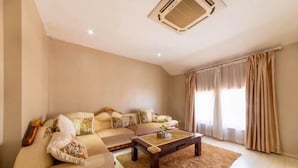 A living room with a sectional sofa, a coffee table, and a large window with curtains. - Xuancheng Guangde Wanjia Express Inn (Guangde)