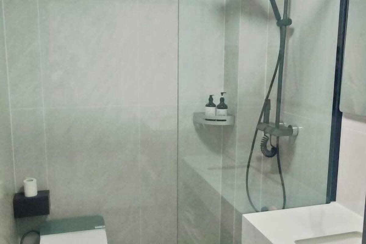 A modern bathroom with a glass shower enclosure, a toilet, and a sink.