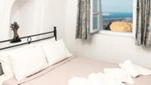 A bedroom with a bed, a window with curtains, and a view of the sea. - Impeccable Double Bed Villa in Imerovigli Santorin (Santorini)