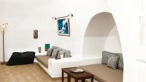 A cozy living room with a sofa, a small table, and a lamp. - Impeccable Double Bed Villa in Imerovigli Santorin (Santorini)