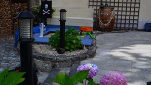 Un jardín con una bandera pirata decorativa, un farol y un coche de juguete.