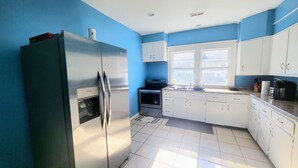A kitchen with white cabinets, a stainless steel refrigerator, a window, and a tiled floor. - Bright & Cozy, near downtown & hiking trails (Birmingham)