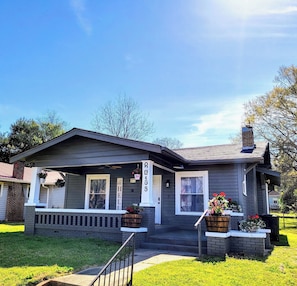 A residential house with a front porch, a brick chimney, and a mailbox.