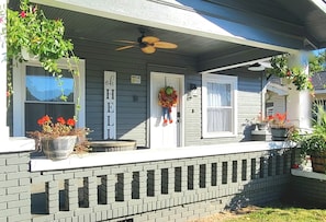 A house with a porch, a door with a wreath, and potted plants.