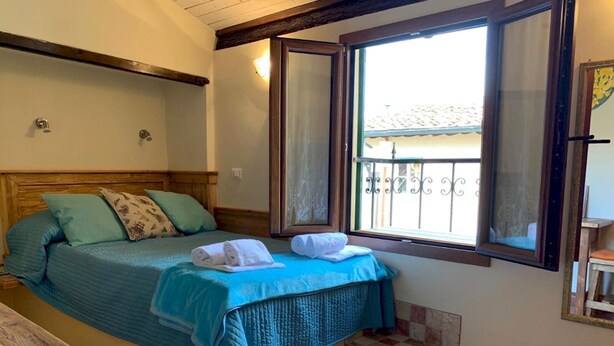 A bedroom with a bed, a window, a small table, and a wooden bench. - Appartamento Volta Della Vecchia (Florence)