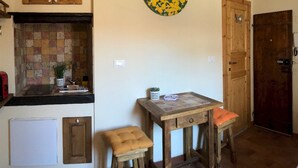 A kitchen with wooden cabinets, a tiled backsplash, a small table with a chessboard, and a wall-mounted decorative plate. - Appartamento Volta Della Vecchia (Florence)