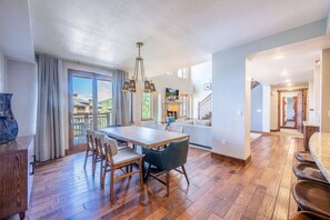 A spacious living area with a wooden floor, a dining table, and a sofa.