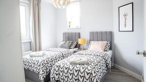 Ein modernes Schlafzimmer mit einem Doppelbett, einem Nachttisch mit Lampe und einem gerahmten Bild an der Wand.
