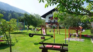 A playground with swings, slides, and a bench. - Ferienwohnung Gederer für 2-5 Personen (Bernau am Chiemsee)