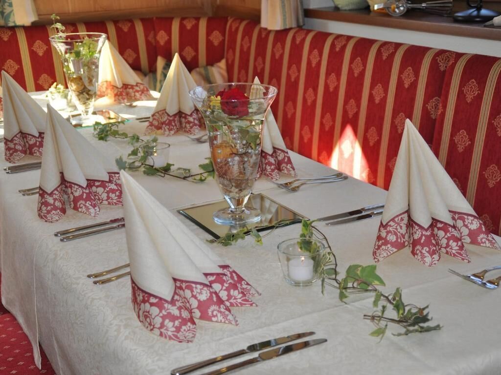 Een gedekte tafel met witte tafelkleden, rode en witte servetten en transparant glaswerk.