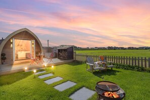 Een knus, halfopen houten blokhut met een patio, een jacuzzi en een barbecue.