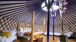 A yurt with a wooden bed, a small wooden chest, and a central heating stove. - Kestrel Yurt, with hot tub, Hawes, Yorkshire Dales (Askrigg)
