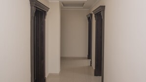 A hallway with a tiled floor, white walls, and dark wooden doors. - Helena Apartments (Budva)