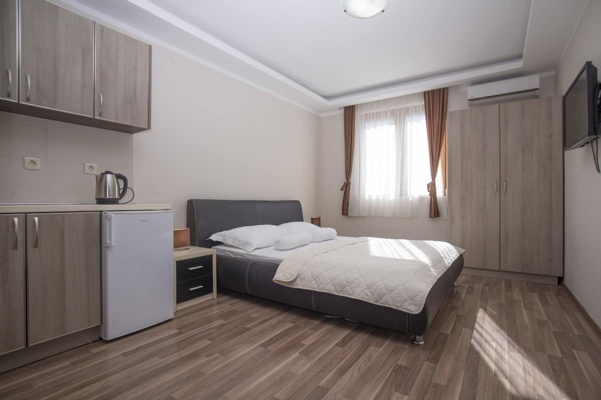 Ein Schlafzimmer mit einem Bett, einer kleinen Küchenzeile und einem Kleiderschrank.