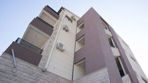 A multi-story building with a stone facade and balconies. - Helena Apartments (Budva)