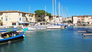 Un port de plaisance avec des bateaux amarrés, des bâtiments dotés de balcons et un ciel bleu dégagé.