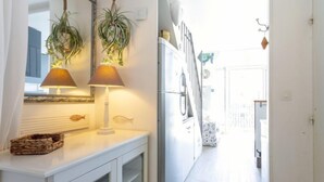 Un couloir avec une armoire blanche, deux lampes et des plantes suspendues.