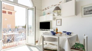 Un balcon avec une table dressée pour le repas, un téléviseur et des objets décoratifs accrochés au mur.