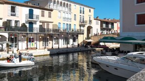 Un canal où sont amarrés des bateaux, un immeuble doté de balcons et un restaurant avec une terrasse.