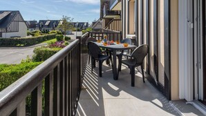 Un balcon avec une table et des chaises, donnant sur une rue résidentielle.