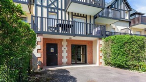 Un bâtiment à deux étages avec une porte noire, une petite fenêtre et un balcon.