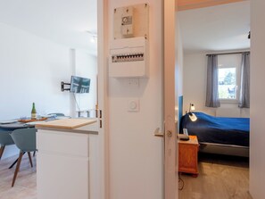 Une chambre avec un lit, un bureau et une chaise, une télévision et une fenêtre avec des rideaux.