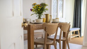 A dining table with two chairs, a vase with flowers, and a gold pitcher. - Brook House, Askrigg, Yorkshire Dales (Askrigg,)
