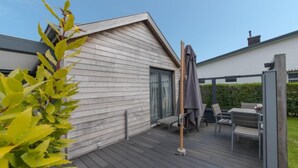 A deck with outdoor furniture, a pergola, and a view of a modern house. - Klemskerkestraat with terrace by Interhome (Bredene)