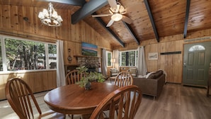 A wooden interior with a dining table, chairs, a sofa, and a fireplace.
