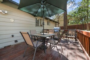 Un patio con mesa y sillas, una parrilla y una sombrilla.