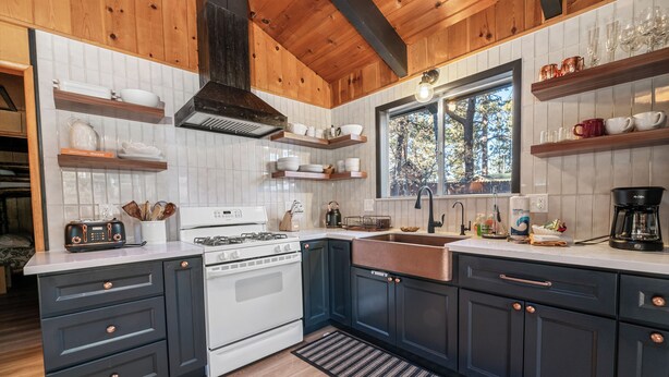 A modern kitchen with dark cabinetry, white subway tiles, and wooden accents.