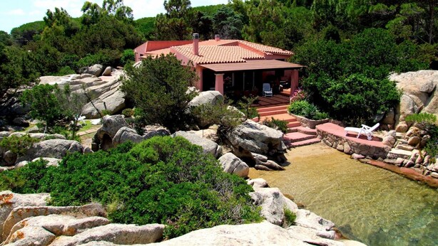 A red-roofed villa surrounded by large rocks and greenery, with a clear pool in the foreground. - Villa Mica in La Maddalena (La Maddalena)