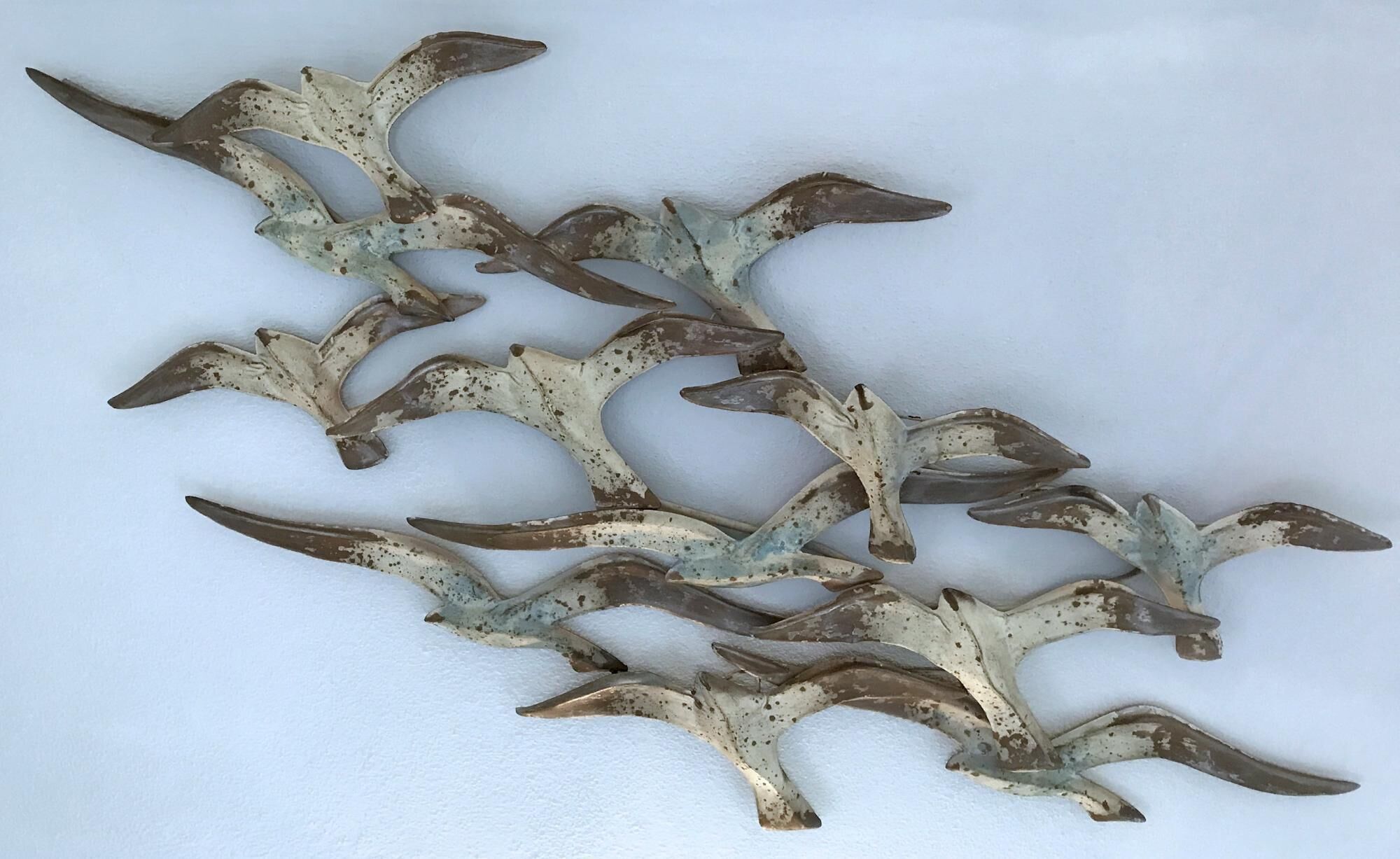 Una escultura de aves en vuelo, fijada a la pared.
