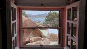 A room with a large window overlooking a rocky landscape and a body of water. - Villa Mica in La Maddalena (La Maddalena)