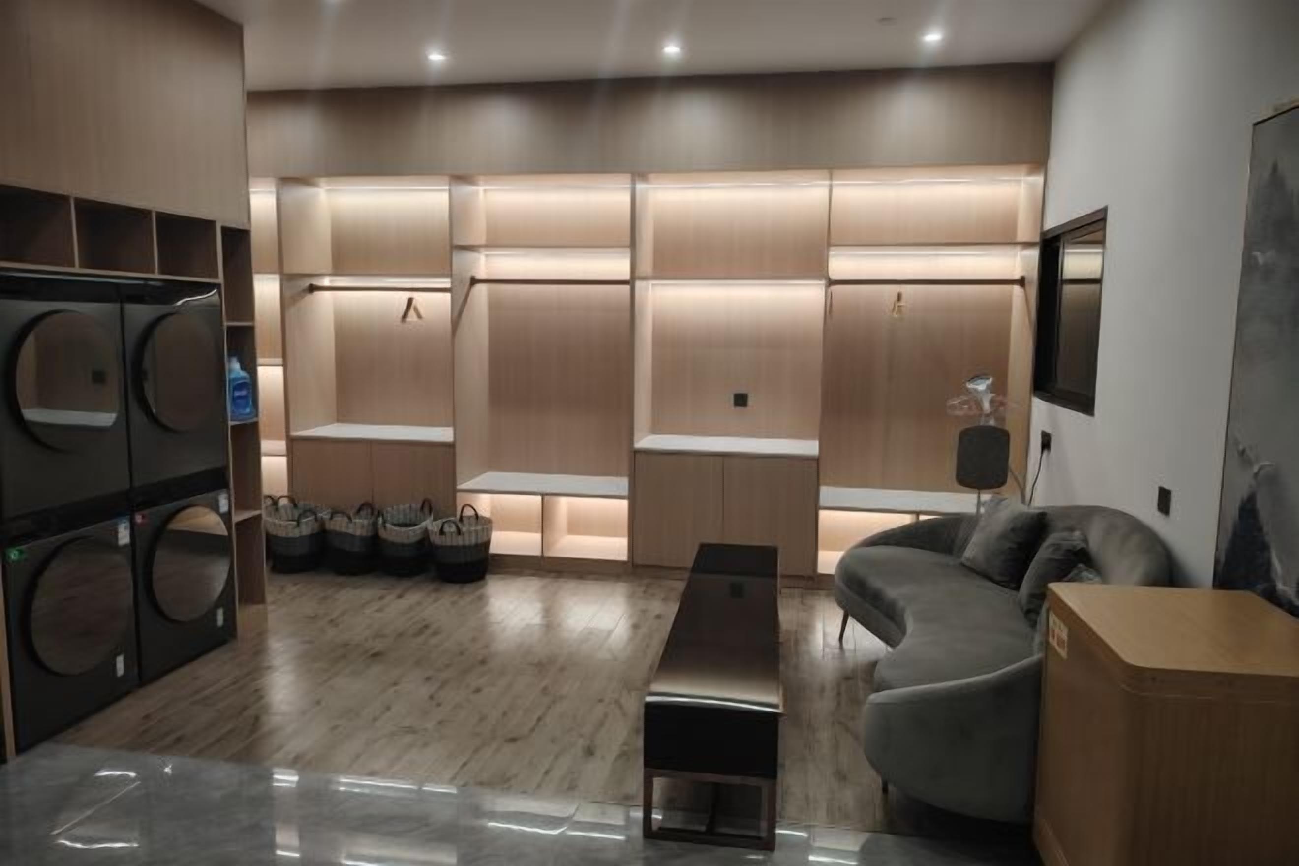 A modern living room with a grey sofa, a wooden coffee table, and built-in laundry facilities.