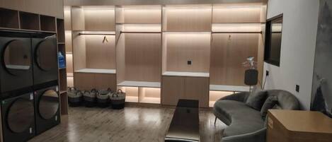 A modern living room with a grey sofa, a wooden coffee table, and built-in laundry facilities.