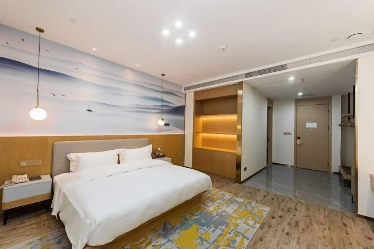 A hotel room with a bed, nightstand, wall art, and a built-in shelf.
