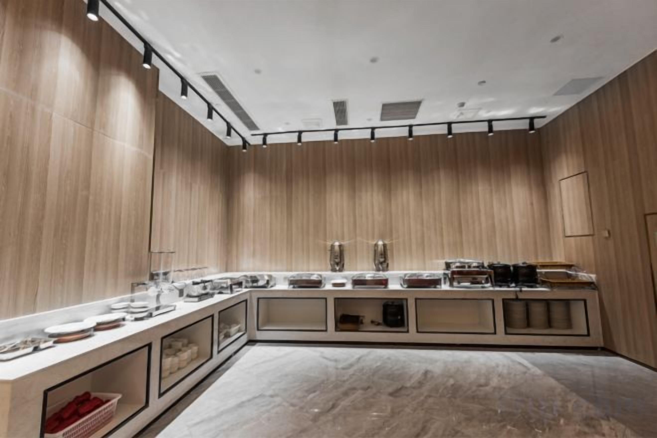 A modern kitchen with wooden paneling, a marble countertop, and built-in appliances.