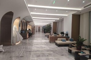 Un vestíbulo de hotel con mostrador de recepción, zona de estar y un largo pasillo.