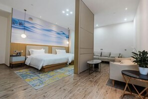 Relax in a spacious room with a large bed, sofa, and wall mural, perfect for unwinding.