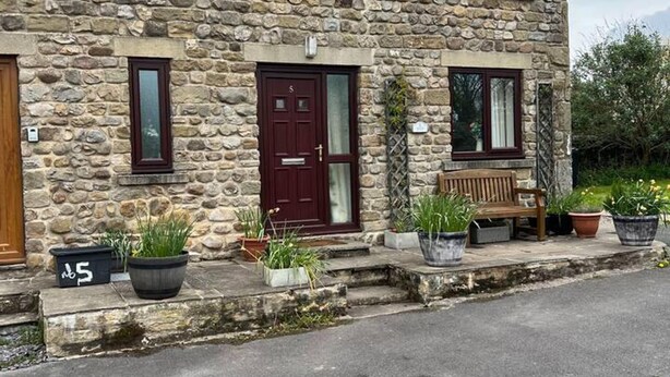 A stone house with a red door, numbered 5, and a bench outside. - Woodside Cottage Grewelthorpe Nr Masham Ripon (Ripon)