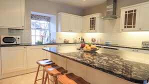 Una cocina moderna con gabinetes blancos, encimera de mármol y taburetes de madera.