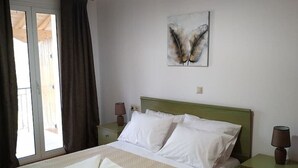 Un letto rifatto con lenzuola bianche, una testiera verde e un’opera d’arte appesa al muro.
