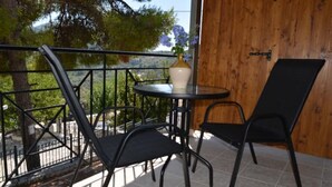 Un balcone con un tavolo e due sedie, un vaso con fiori e un muro in legno.