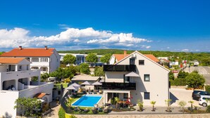 A residential area with a pool, white buildings, and a clear blue sky. - Villa LuiSole apartment °2 with heated saltwater pool, family-friendly, sea view (Krk)