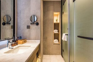 A modern bathroom with two sinks, a mirror, and a shelf with towels. - Fragrans Hotel(Suzhou Lumu Metro Station Branch) (Suzhou)